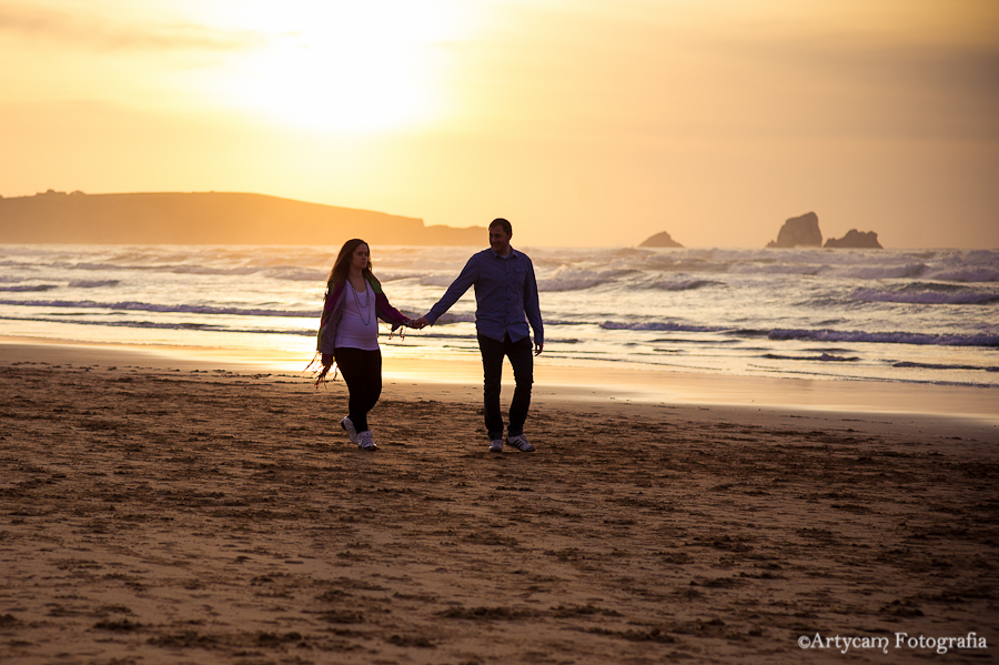 Sesión embarazada atardecer playa Liencres Santander pareja joven caminar playa mano